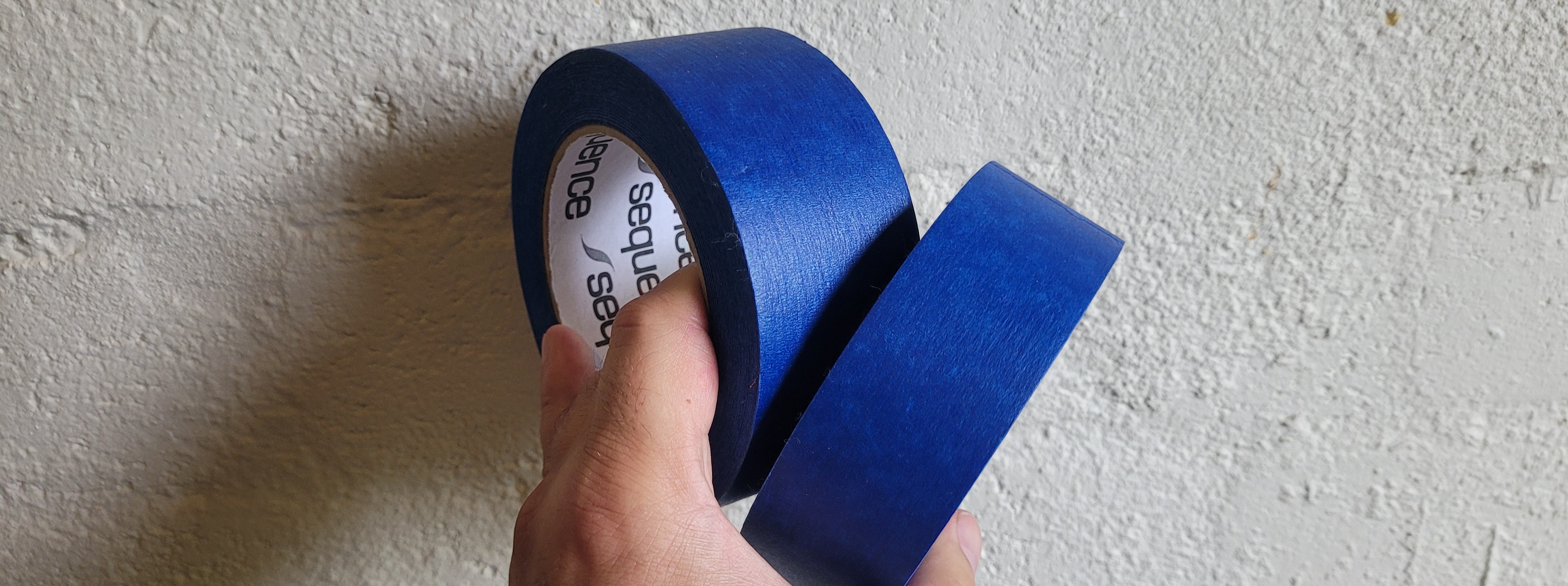 Blue painter's masking tape held against a textured wall